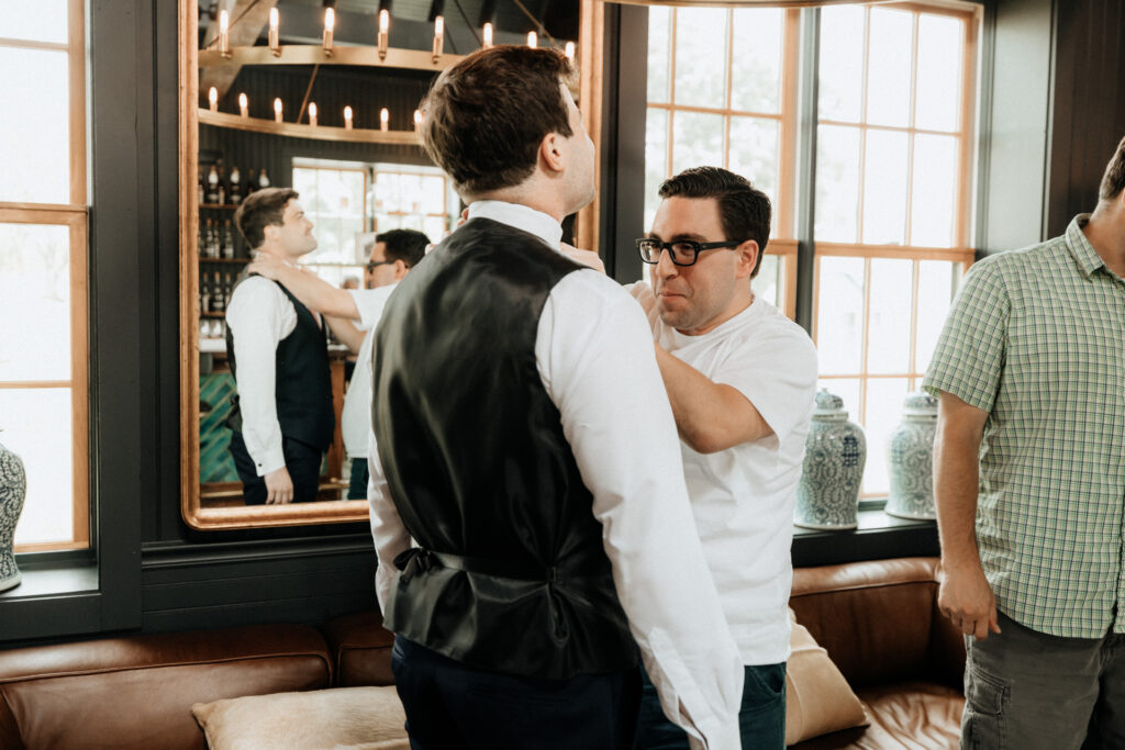 groomsman pinning bowtie on groom while getting ready at valley view farm