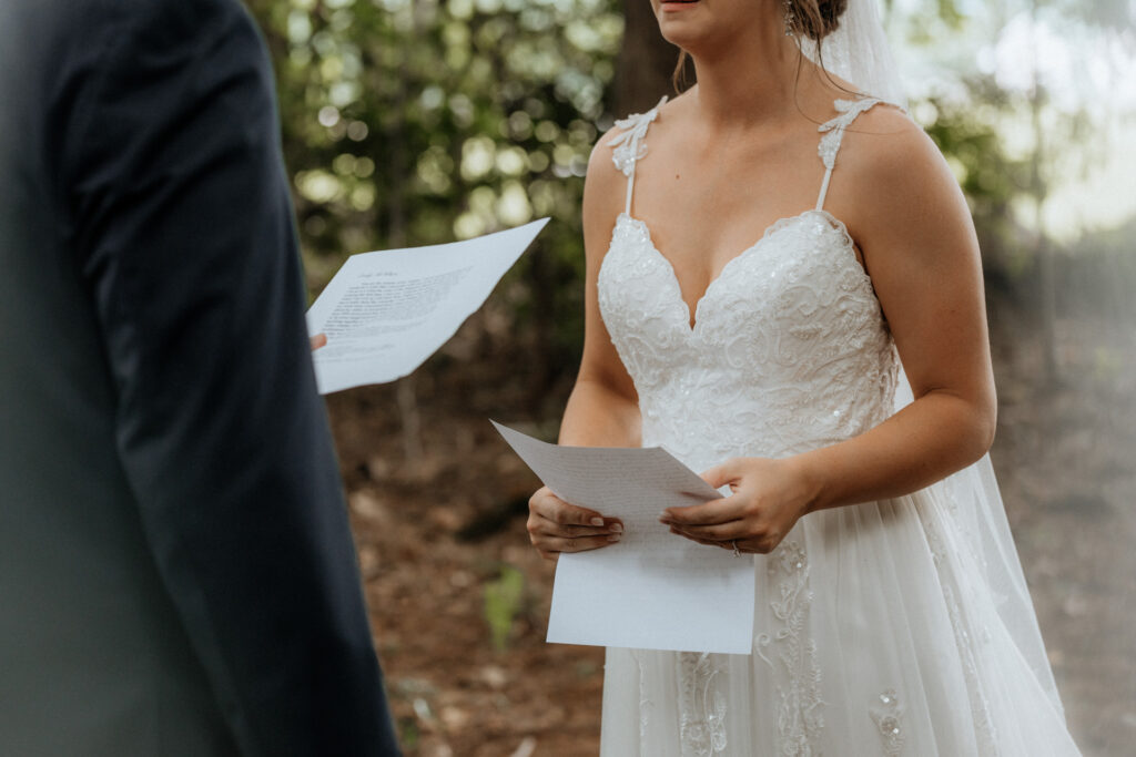 closeup of bride and groom holding vow papers and reading to each other