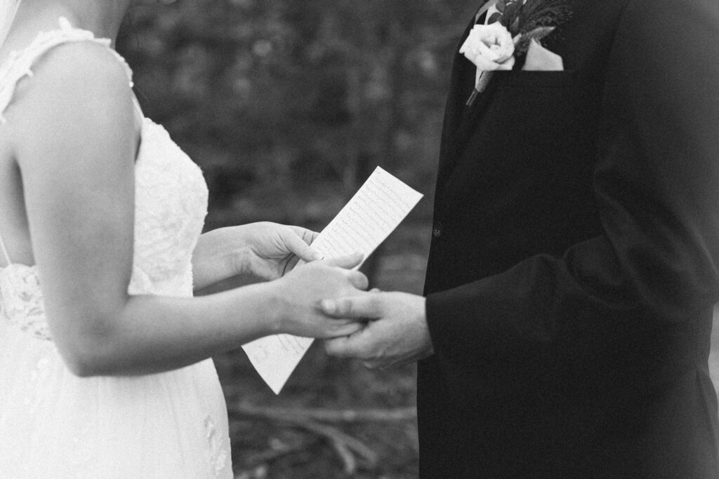 closeup of bride and groom holding vow papers and reading to each other